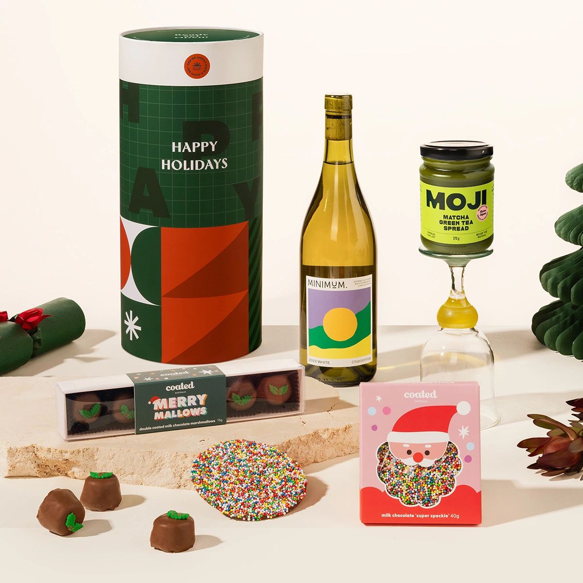Christmas gift hamper including a bottle of wine, a jar of matcha spread, and a box of chocolate coated marshmallows and a speckled milk chocolate.