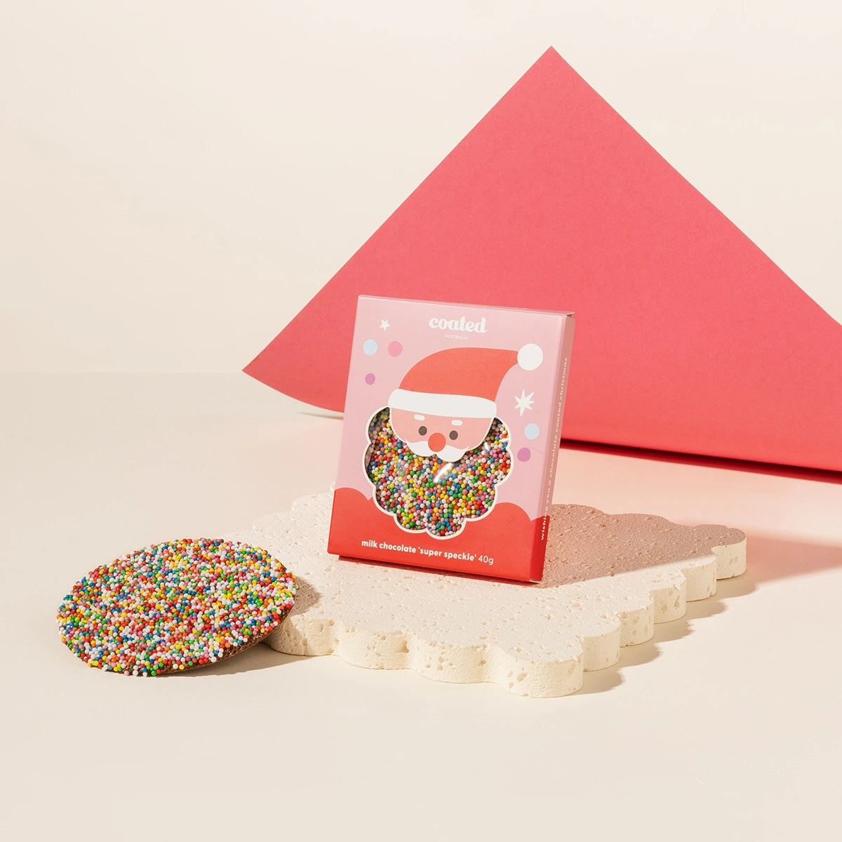 Speckle-coated chocolate with a Santa Claus design on a pink box against a beige background