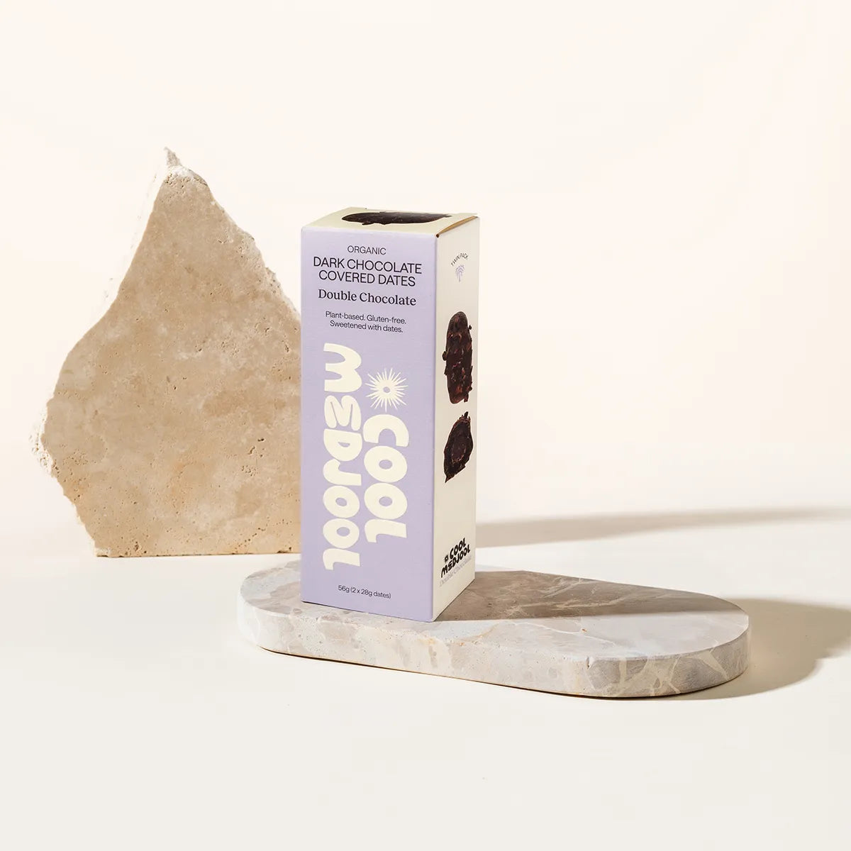 Box of Cool Medjool dark chocolate-covered dates on a marble stand with a white background