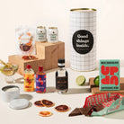Gin & tonic gift hamper with Four Pillars gin, 2 cans of coastal tonic mixers, Lavish blood orange garnish, a tinned candle, and Up-Up chocolate. Packaged in a designed canister.