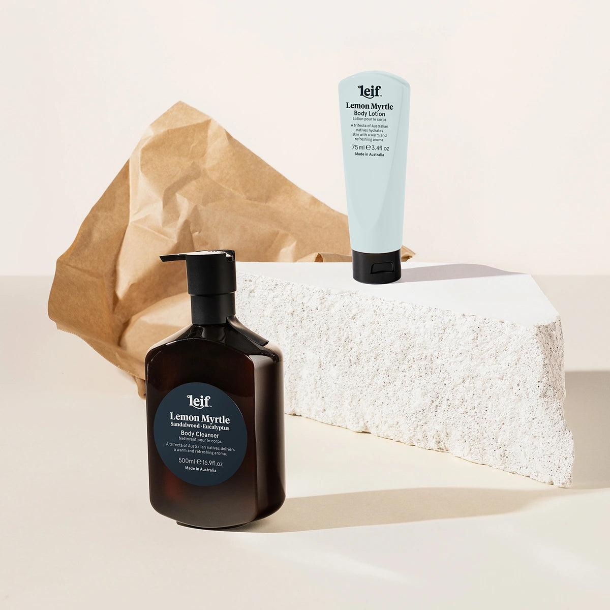 Two Leif products, a bottle and a tube, on a textured surface with a brown paper bag.
