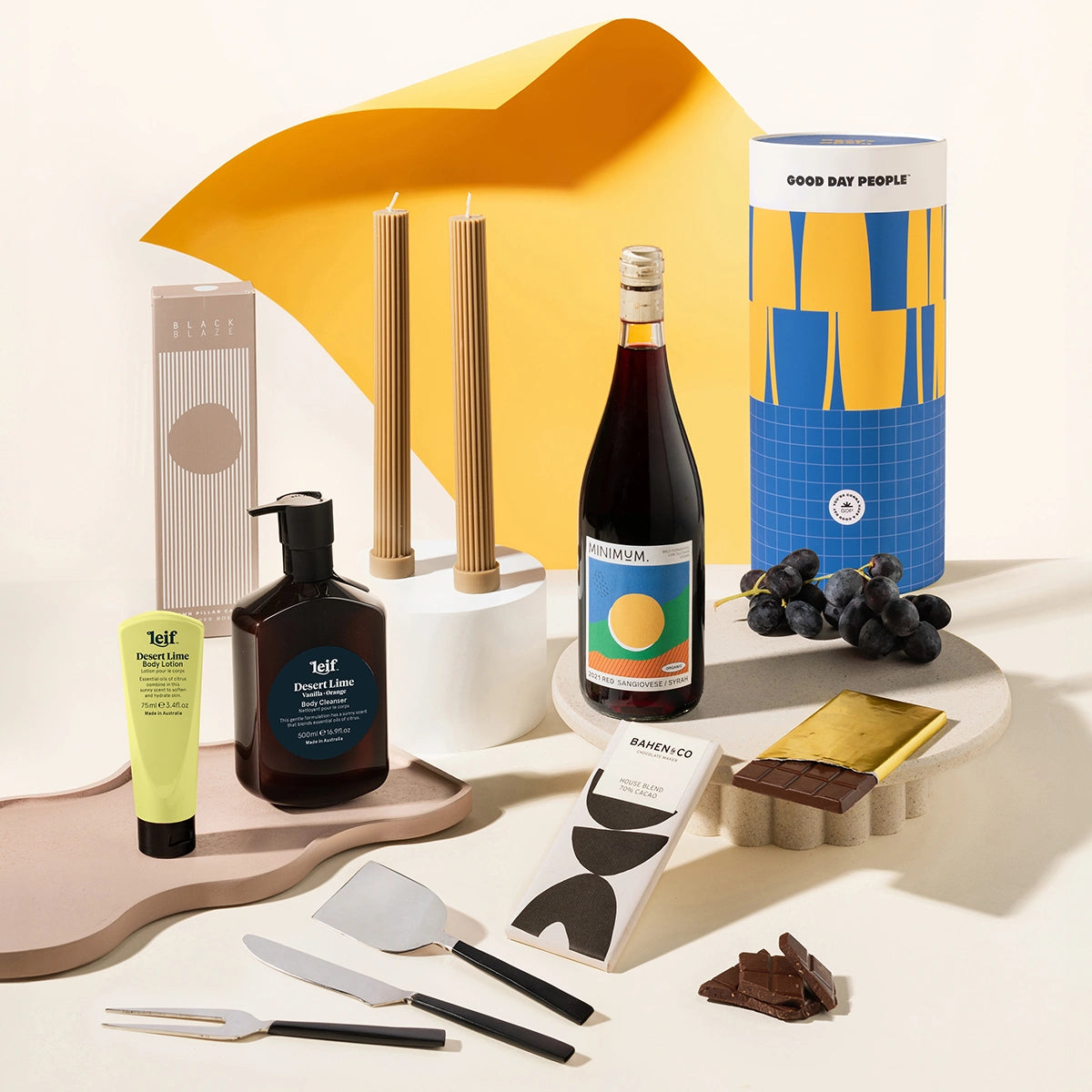Luxurious gift hamper with black blaze pillar candles, a body wash and lotion set from Leif, organic dark chocolate and a stylish set of 3 cheese knives. Packaged in a trendy designed canister.