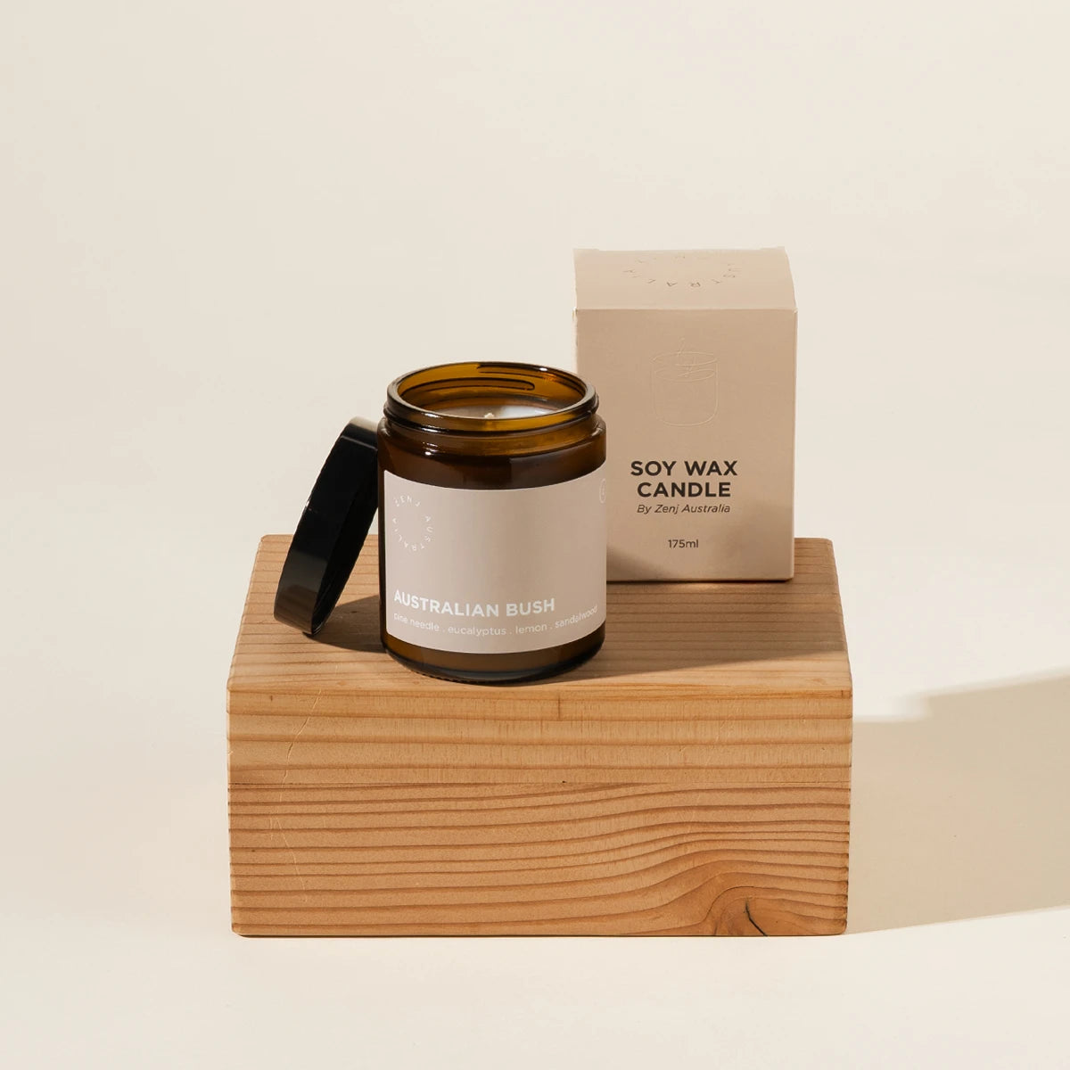 Zenj Candle in their Australian bush scent. Comes in an amber jar and a beige box. Styled product shot showing the jar and box on a timber platform.