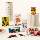 Gourmet gift hamper packaged in a fun canister. The hamper contains olives, Korean BBQ mixed nuts, organic chocolate, rocky road & miso caramel. 