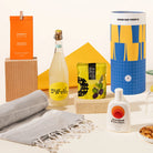 Summer-inspired gift hamper with Zoncello limoncello spritz, Standard procedure sunscreen, olives, a turkish beach towel and nuts, packaged in a fun canister.