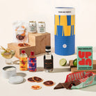 Gin & tonic gift hamper with Four Pillars gin, 2 cans of coastal tonic mixers, Lavish blood orange garnish, a tinned candle, and Up-Up chocolate. Packaged in a designed canister.