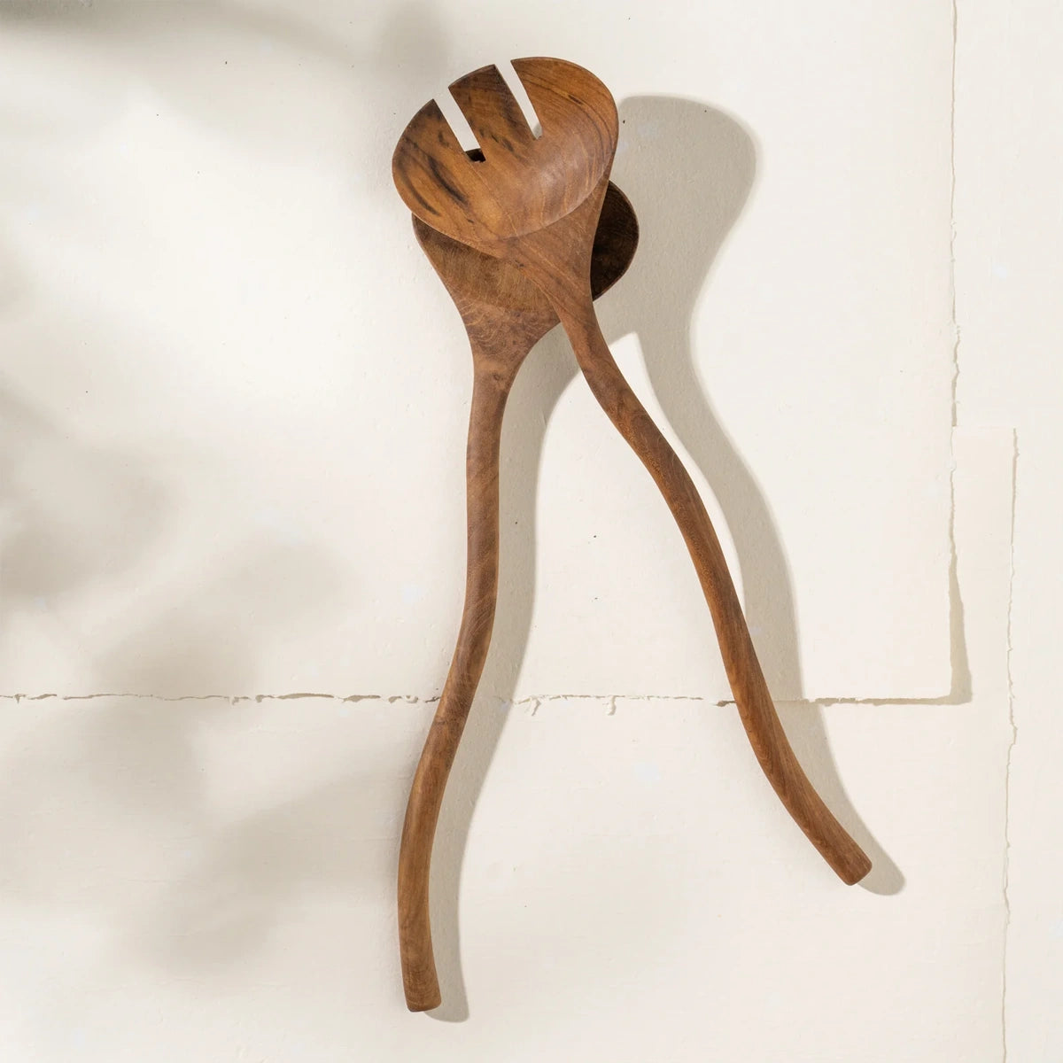 Wooden wavy salad servers on a white background
