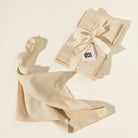 A set of folded cream-colored linen napkins tied with a matching ribbon bow, with one napkin draped in the foreground. 