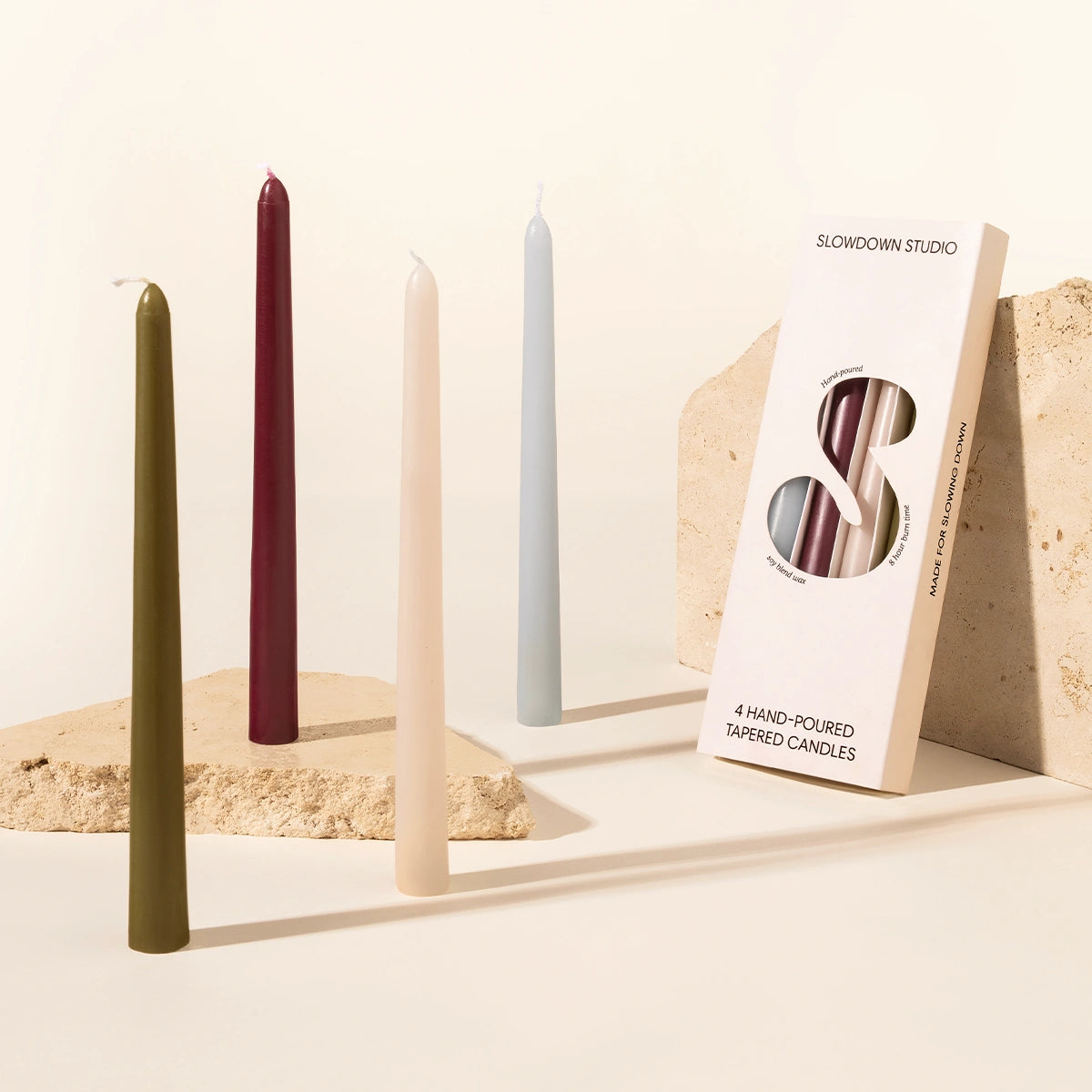 Set of 4 tapered candles in burgundy, olive, cream and duck egg blue. They come in a carton with an artsy S cutout on the front which displays the colours of each candle inside.