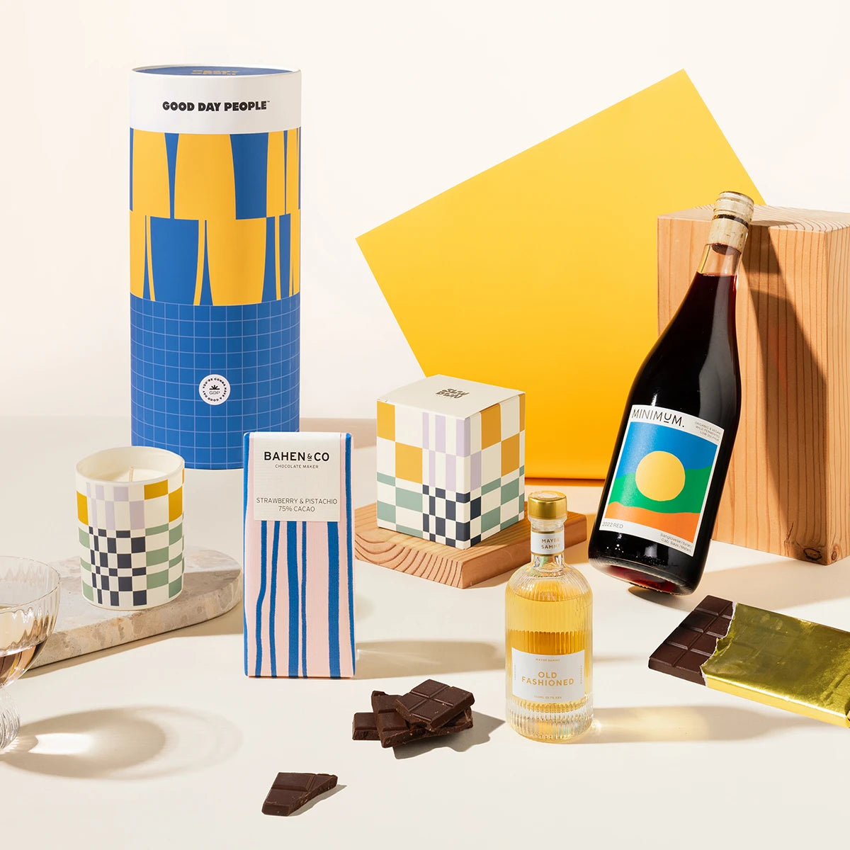 Styled shot of gift hamper with blue and yellow canister. Wine, candle, cocktail and chocolate. 