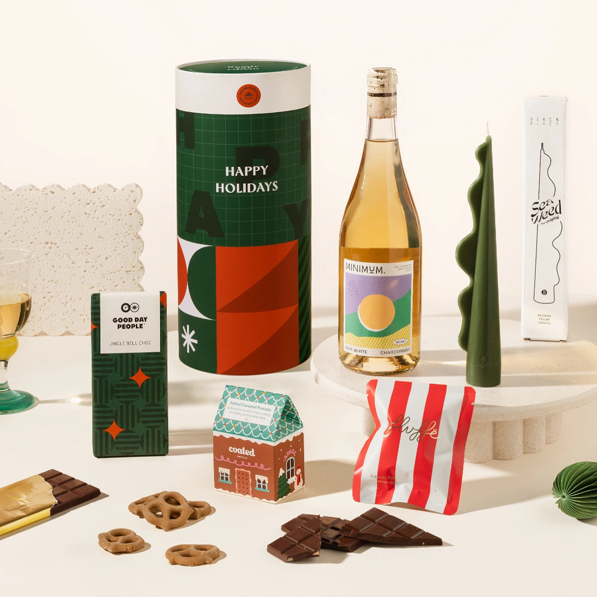 Yuletide Yasmin gift hamper with a sculptural pillar candle, your choice of wine, gingerbread chocolate, salted caramel covered pretzels and fairy floss. Delivered in a fun, designed canister. 
